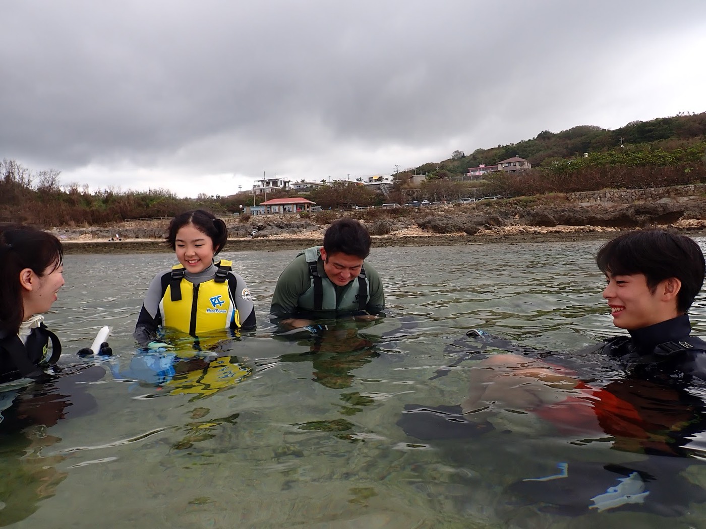 浅瀬でライフジャケットを着用し、笑顔で談笑する参加者とガイド