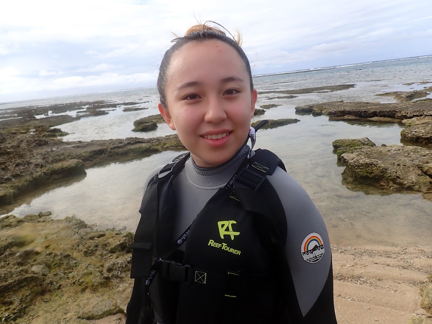 天然水族感あふれるリーフでライフジャケットを着て笑顔の女性