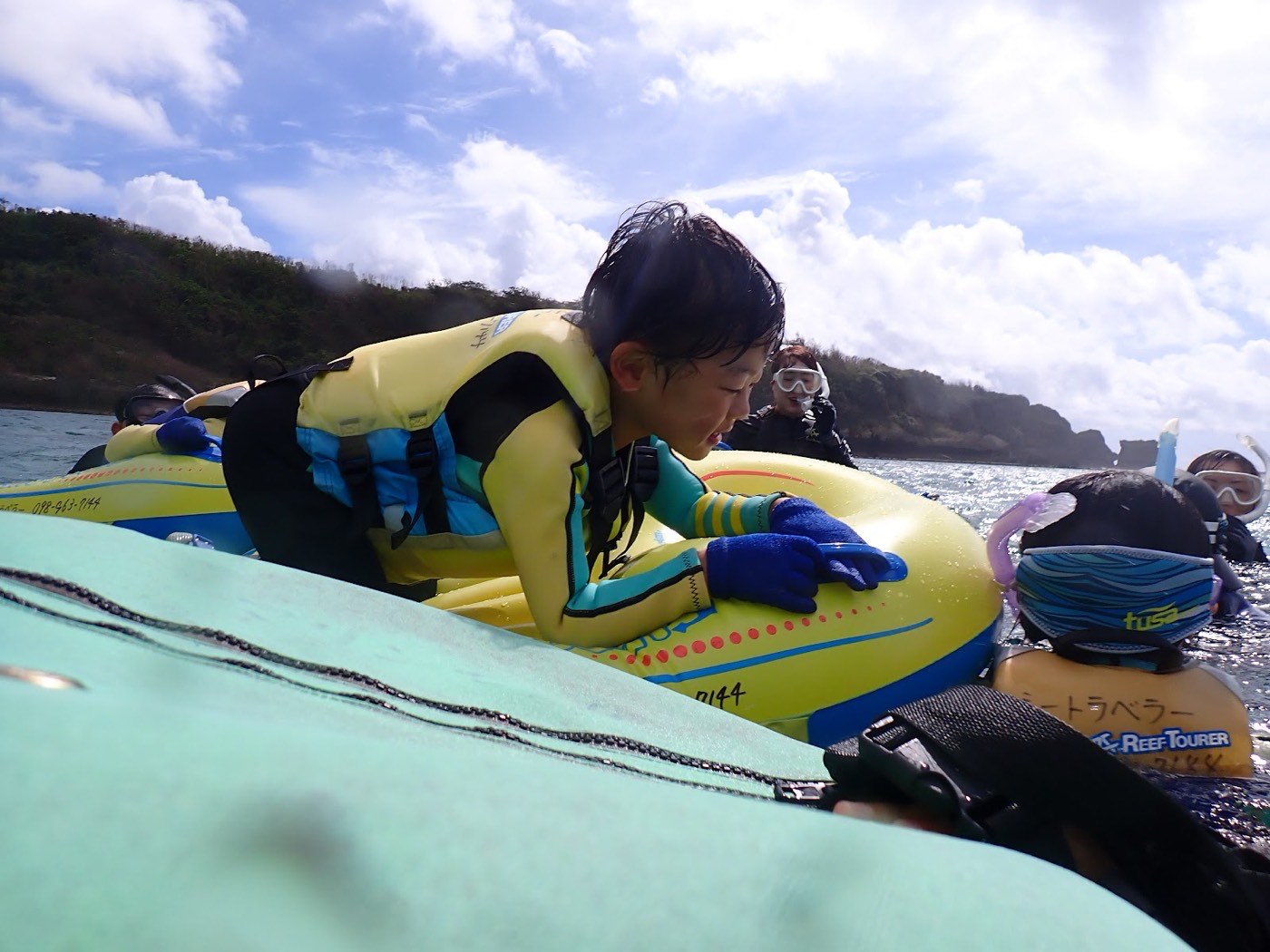 水面に浮かぶフロートにつかまり、楽しそうに周囲を見る子供たち