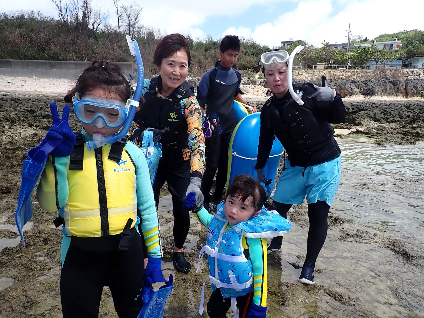 浜辺でガイドと参加者が器材を準備している様子。奥には天然水族感のロゴと海が見える