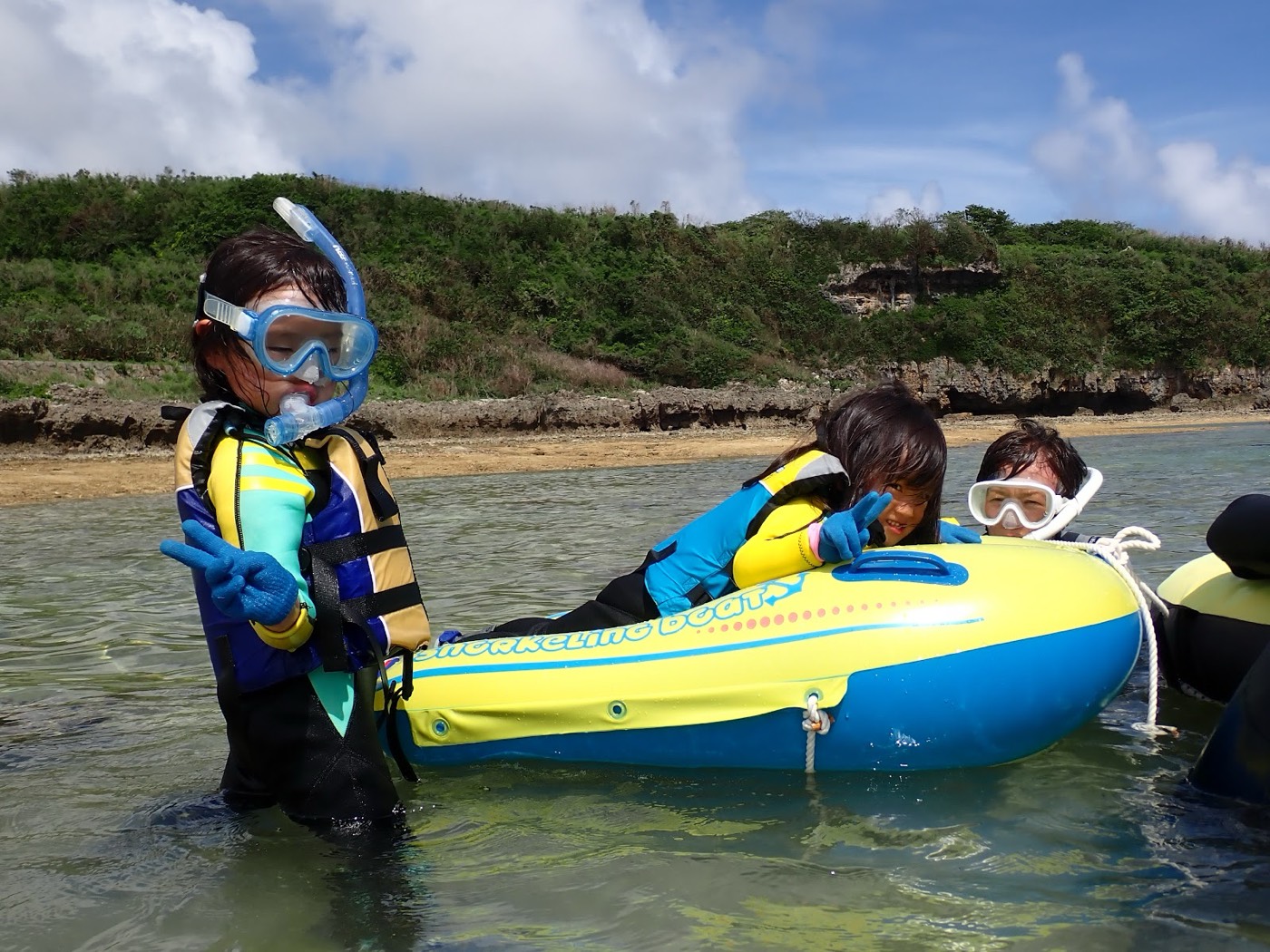 青い空と海岸を背景に、浮き輪に乗った参加者が海に浮かび、笑顔でカメラを見る