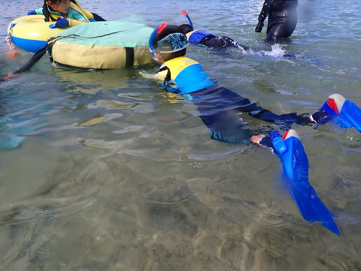 フロートにつかまり水慣れ練習をする参加者とガイド。水面は穏やか
