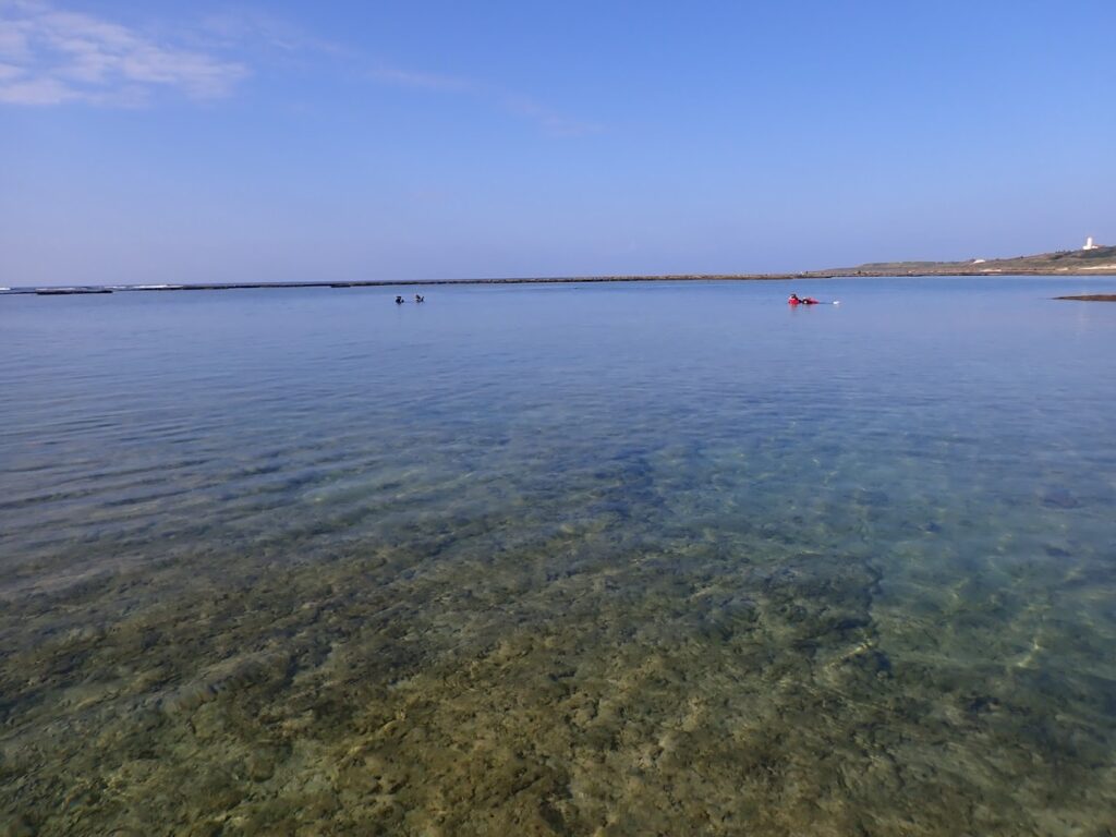 大度海岸の穏やかなリーフと澄んだ浅瀬。遠くにガイドと参加者が見える
