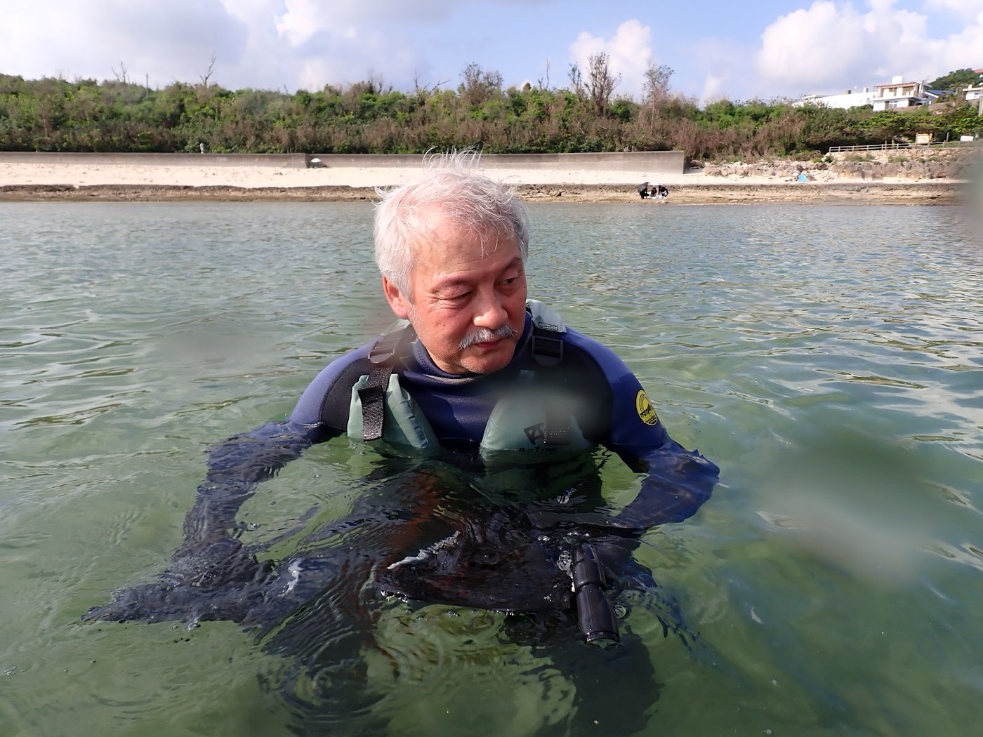 浅瀬でマスクをつけ水面を覗き込む年配の参加者