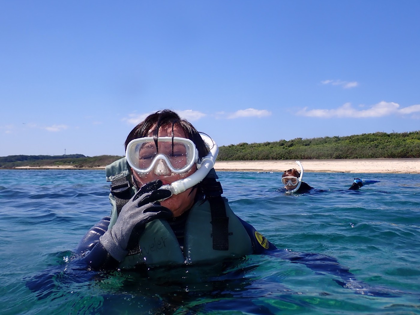 水面に浮かび、シュノーケルマスクをつけて海を見る女性